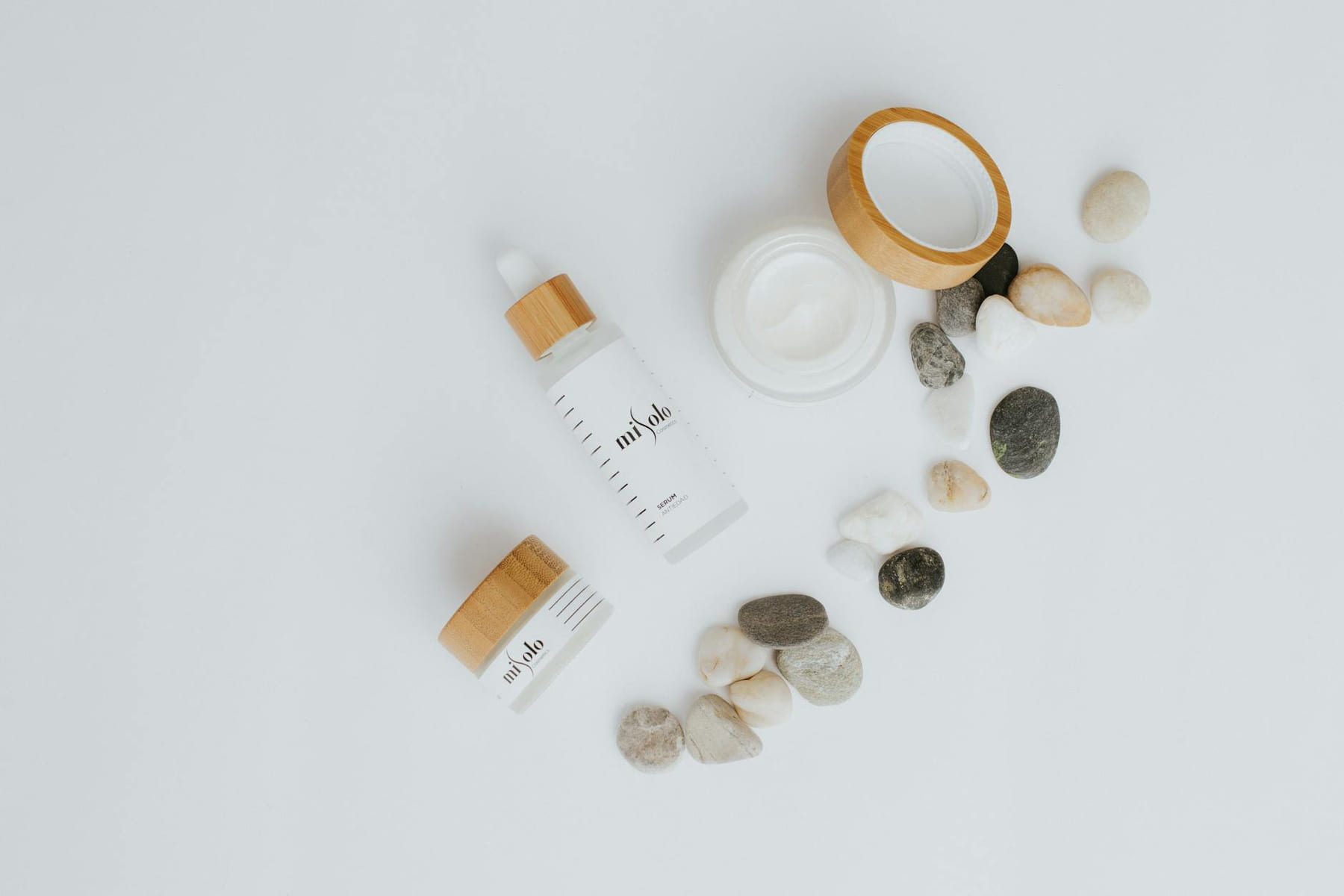 A flat lay of skincare bottles and jars with stones on a white background. on Purely Polished