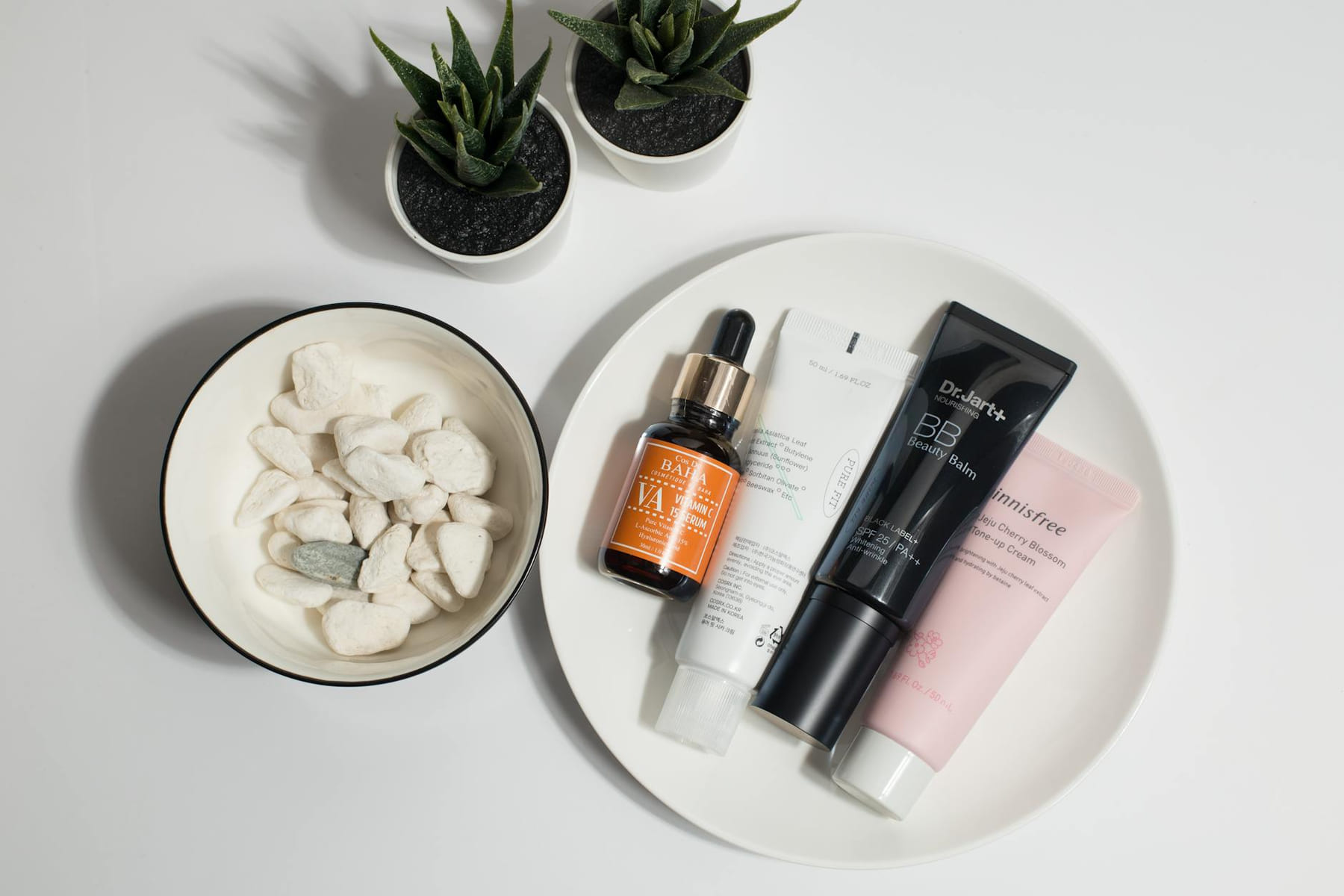A flat lay of skincare products on a plate with decorative elements. on Purely Polished