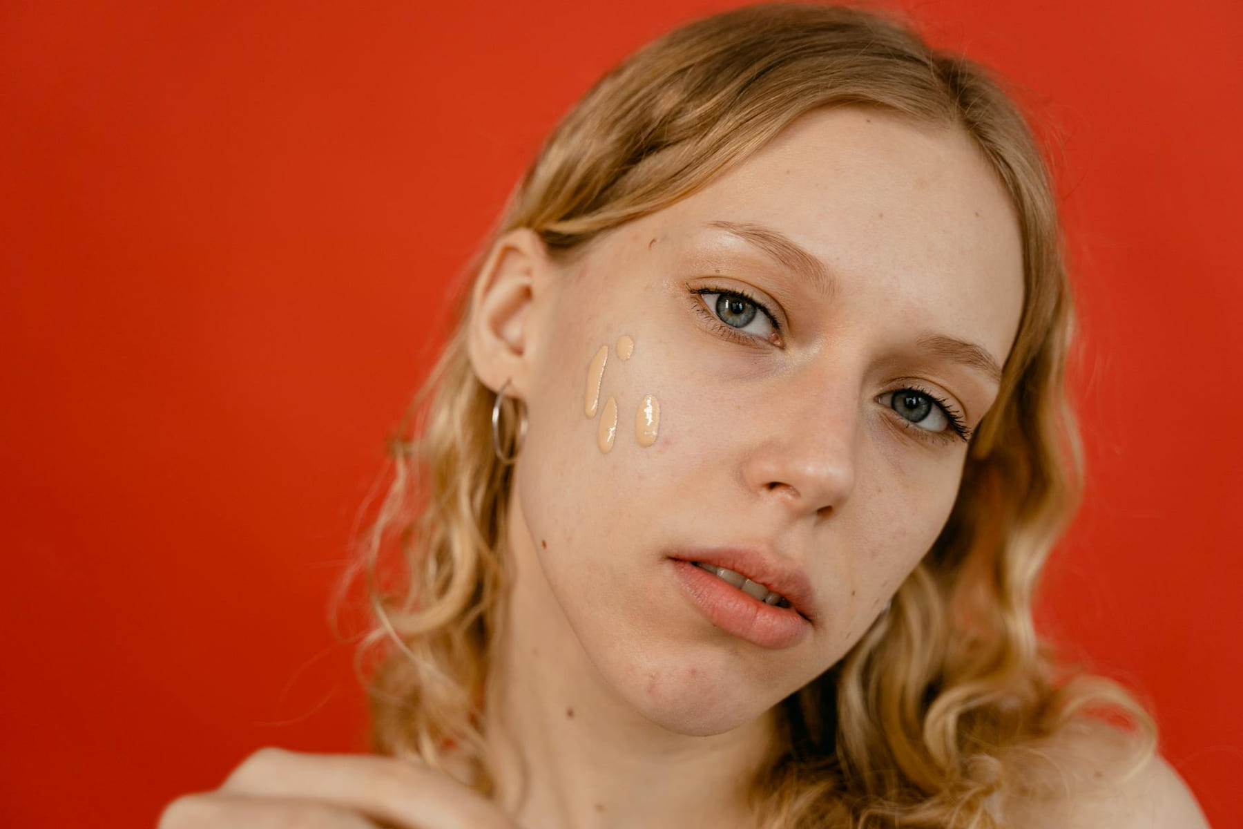 A close-up portrait of a woman applying foundation, showcasing natural beauty and skincare. on Purely Polished