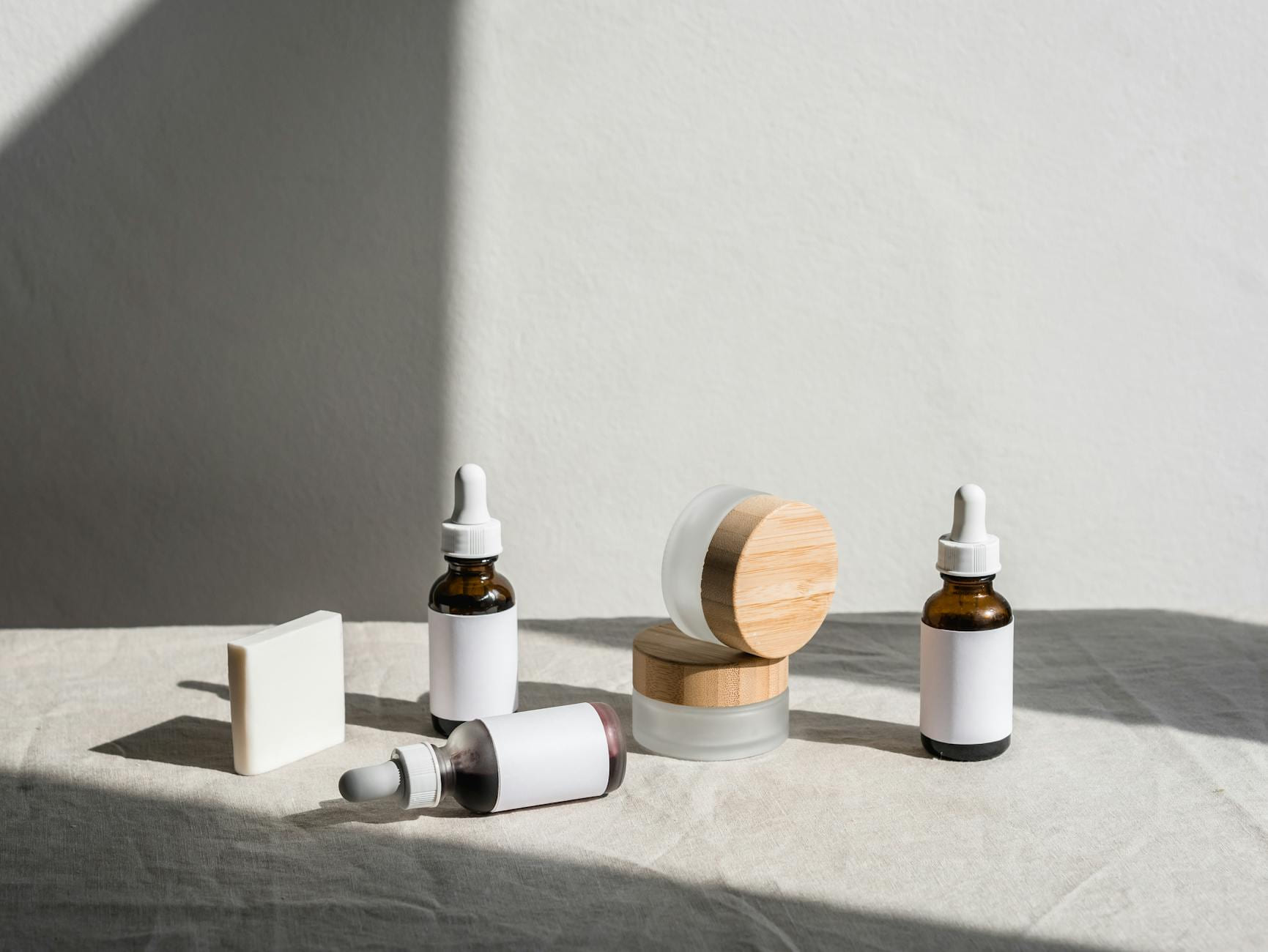 Flat lay of skincare products in jars and dropper bottles under soft natural light. on Purely Polished
