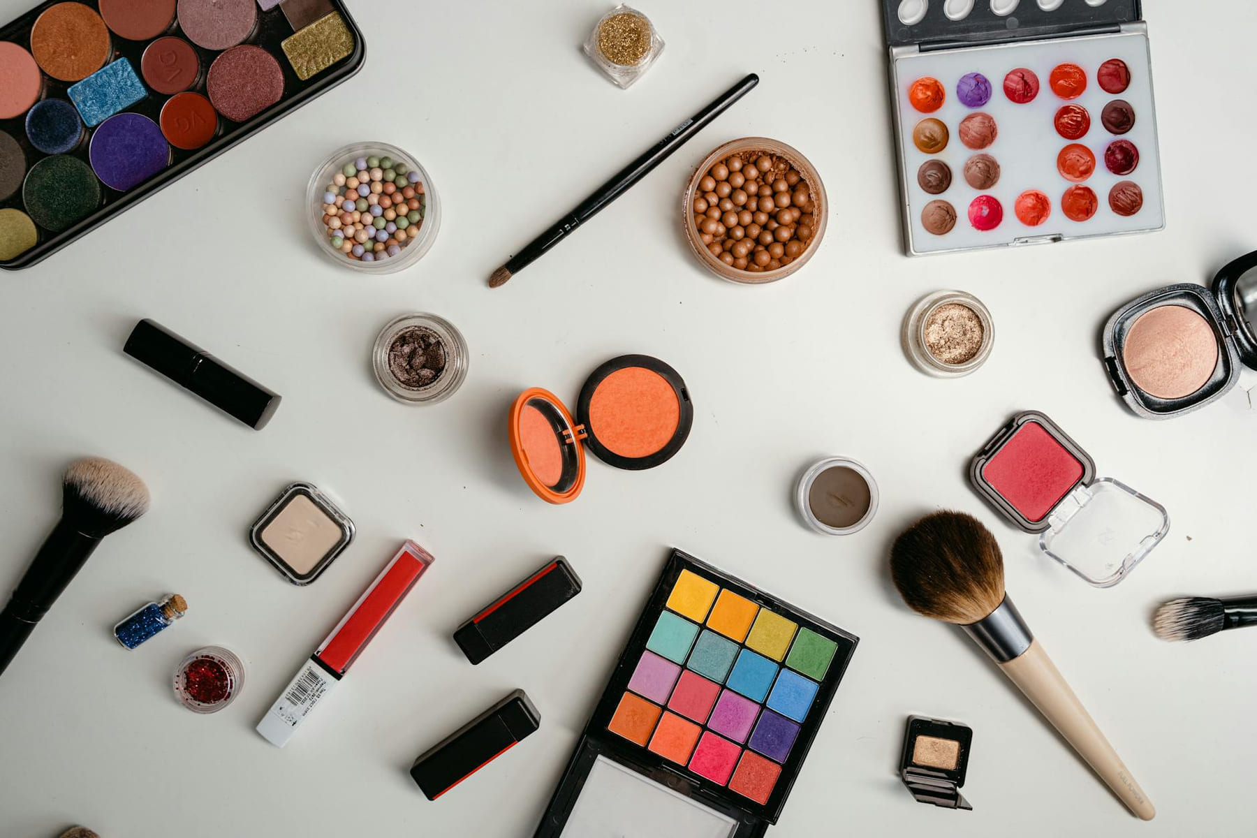 A vibrant collection of makeup and beauty products arranged in a flat lay on a white background. on Purely Polished