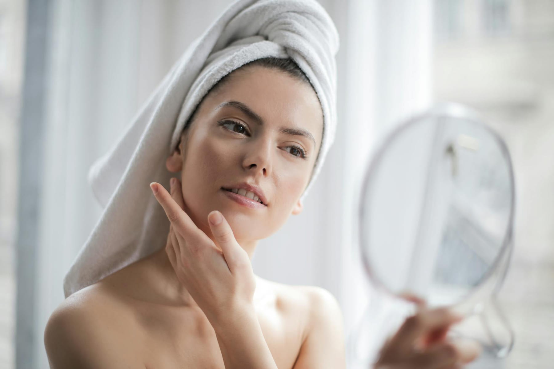 A serene and elegant woman enjoys a skincare ritual, enhancing her natural beauty in the comfort of her home. on Purely Polished